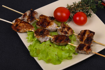 Pork kebab skewers in the plate with salad leaves and tomatoes