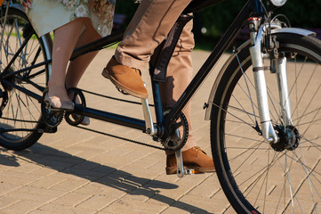 Fototapeta premium The couple man and woman ride tandem bike on the road