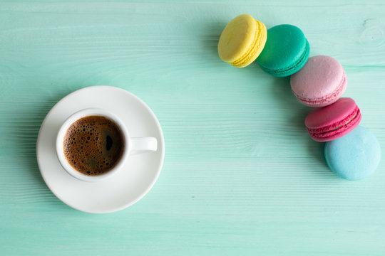 Pastel macarons around a coffee cup