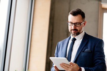 Middle aged handsome businessman in suit at office.