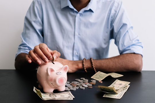 Man adding coins in piggy bank