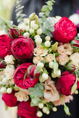 Beautiful wedding bouquet of bright red flowers, with beige roses.