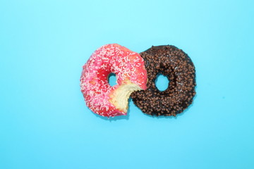 Pink and chocolate donuts isolated on blue background, creative minimalism