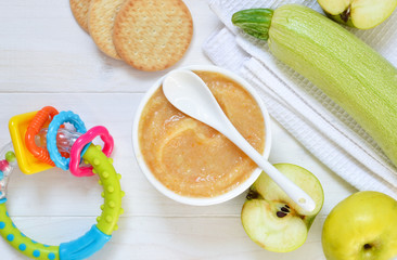 Baby food from 6 months. Vegetable puree from courgettes, stamps and potatoes on a concrete background. Food for newborns.