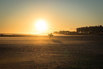 Naklejka premium surfer on beach at sunset in Queens