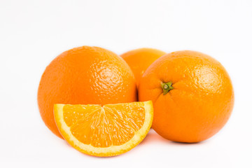 Three fresh juicy oranges and one slice lobule isolated on white background. Close photo