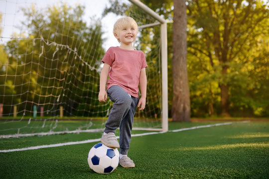Little boy having fun playing a soccer/football game on summer day. Active outdoors game/sport for children.