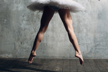 Ballerina slim legs. Young beautiful woman ballet dancer, dressed in professional outfit, pointe shoes and white tutu. © primipil