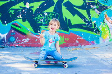 small kid on a skateboard doing the shaka sign