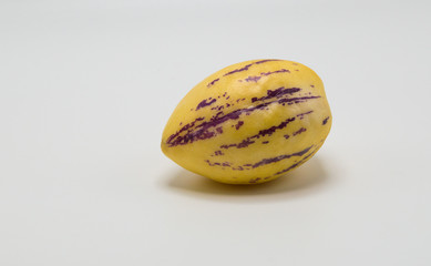 one ripe yellow pepino melon with purple stripes isolated on white