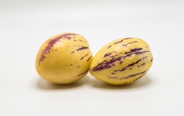two ripe yellow pepino melons with purple stripes isolated on white