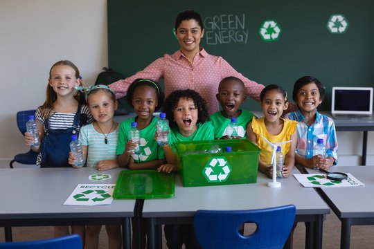 Happy schoolkids and teacher looking at camera in classroom