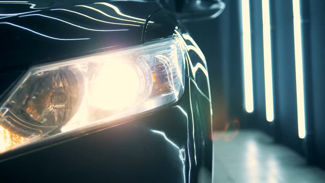 Radiating headlight of a black car in a workshop