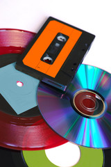 CD, disque vinyle rouge et noir et cassette audio sur fond blanc