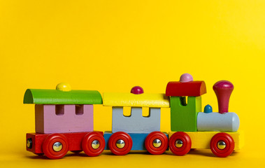 Colorful wooden train isolated over yellow background.