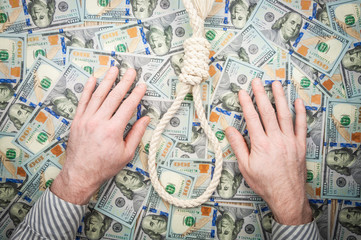 Men's hands with loop of rope on background of dollars. top view