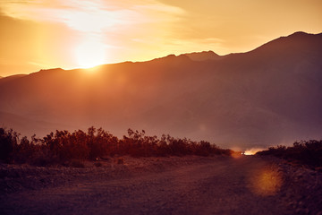 desert road with truck in the distance at sunrise