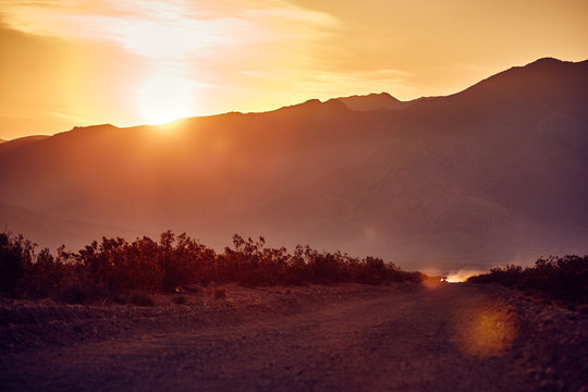 desert road with truck in the distance at sunrise