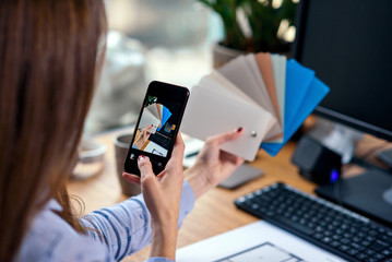 Close up shot of woman hands taking photo of color palette in the modern office. View from the back