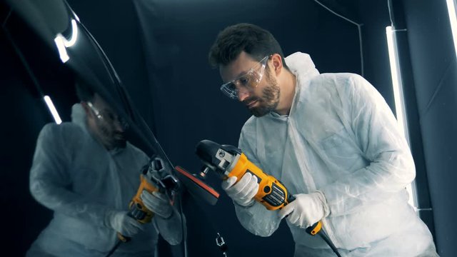 Serviceman is buffing a vehicle with a mechanized device