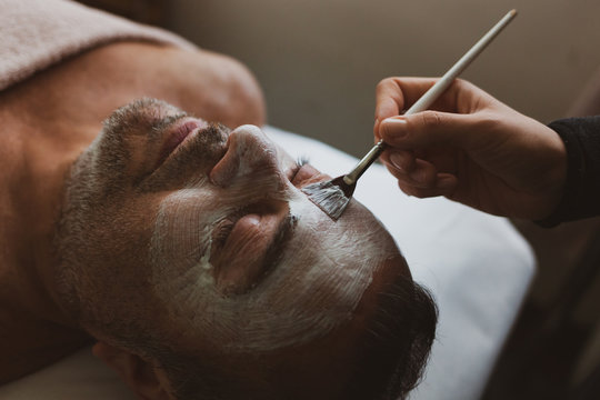 Middle-aged man in a spa with a facial mask.