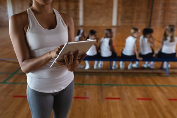 Mid section female basketball coach using digital tablet at - Powered by Adobe