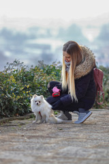 Bella ragazza sorridente gioca con cane bianco. Spitz tedesco nano toy. Volpino di Pomerania.	
