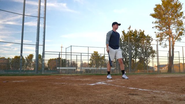 An Amateur Baseball Player Hits A Foul Ball At Home Plate During A Team Practice In The Park At Sunset.