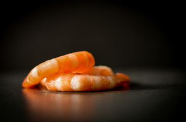 Pile of cooked seafood shrimps prawns on black dark background
