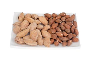 Dried peeled and unpeeled whole almonds on white plate