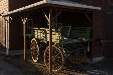 Old horse-drawn wagon under cover and lit by the last rays of the setting sun. In Murchison, Tasman, New Zealand.