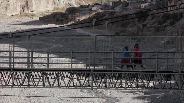 Aboriginal Women Crossing Suspension Bridge over the Colanzuli River in Iruya, Salta Province, Argentina.