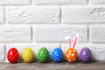 Decorated Easter eggs on table near brick wall. Space for text