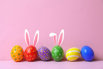 Decorated Easter eggs on table near color wall. Space for text