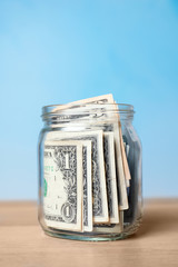 Donation jar with money on table against color background