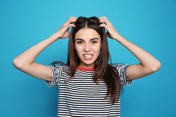 Young woman scratching head on color background. Annoying itch