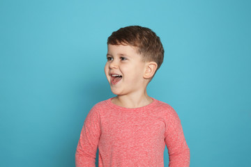 Portrait of little boy laughing on color background