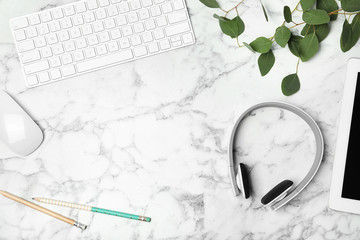 Flat lay composition with headphones, computer keyboard and space for text on marble background