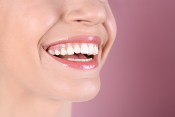 Obraz premium Young woman with healthy teeth and beautiful smile on color background, closeup. Space for text