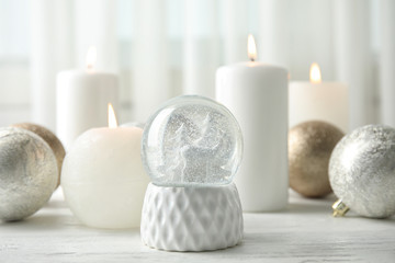 Obraz na płótnie Canvas Snow globe with Christmas balls and candles on table