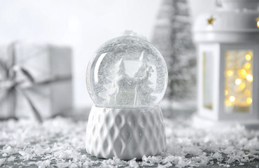 Snow globe with Christmas decorations on table
