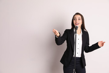 Young businesswoman with microphone on color background. Space for text