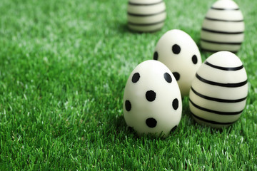 Traditional Easter eggs decorated with black paint on green lawn, space for text