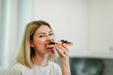 Woman having a toast with blackberry jam and vegan cream cheese