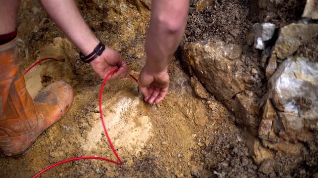 Worker packing explosives into hole drilled in rock