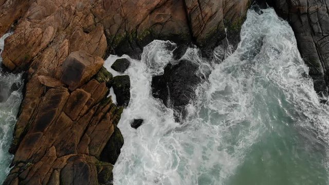 Various aerial movements showing the ocean waves coming in rolling hitting the cliff rocks of Joatinga beach in Rio de Janeiro
