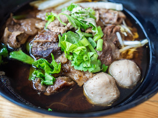 Close up of black bowl of Chinese style beef noodle soup