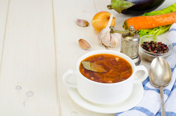 Soup with vegetables on white wooden surface