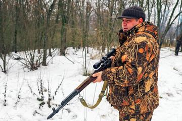 Fototapeta premium Winter hunting. Hunter moving With rifle and Looking For Prey.