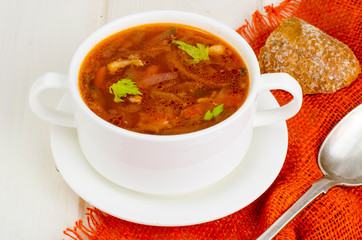 Soup with vegetables on white wooden surface